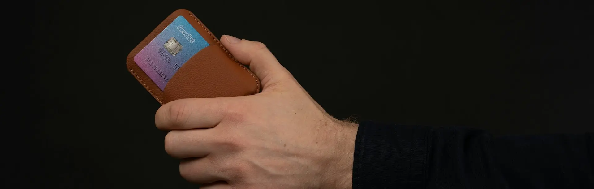 Faites un don en toute sécurité. Nous acceptons toutes les cartes de crédit pour vos contributions DonaTouch. Main insérant une carte bancaire dans un portefeuille en cuir, symbolisant la rapidité et la sécurité du paiement sans contact avec DonaTouch.