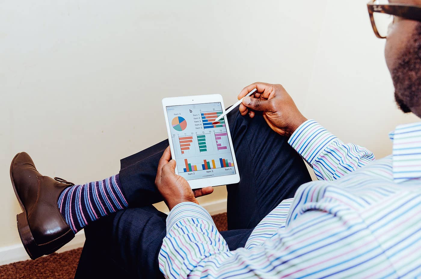 Homme sur ordinateur portable ue par-dessus l'épaule d'une personne tapant sur un ordinateur portable. L'écran affiche un tableau de bord d'analyse de données, avec des graphiques et des indicateurs de performance.